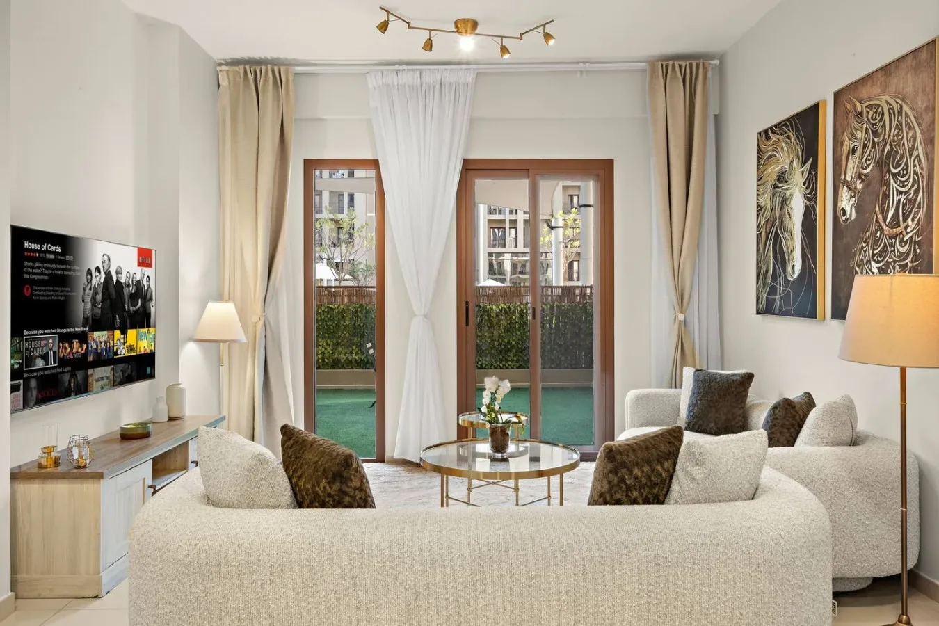 A bright living room with seating, a round table, and glass doors opening to a balcony.