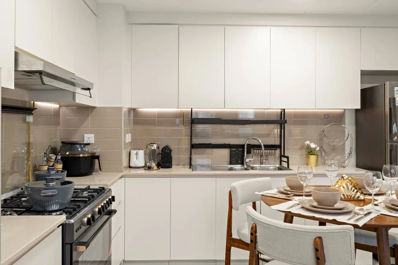 A modern kitchen with a dining table set with dishes and glassware.