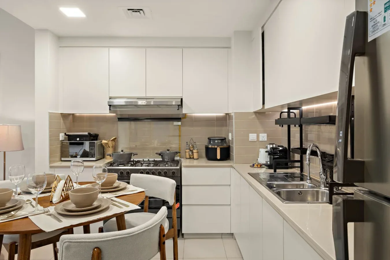 A bright kitchen and dining area with white cabinetry and a table set for a meal.