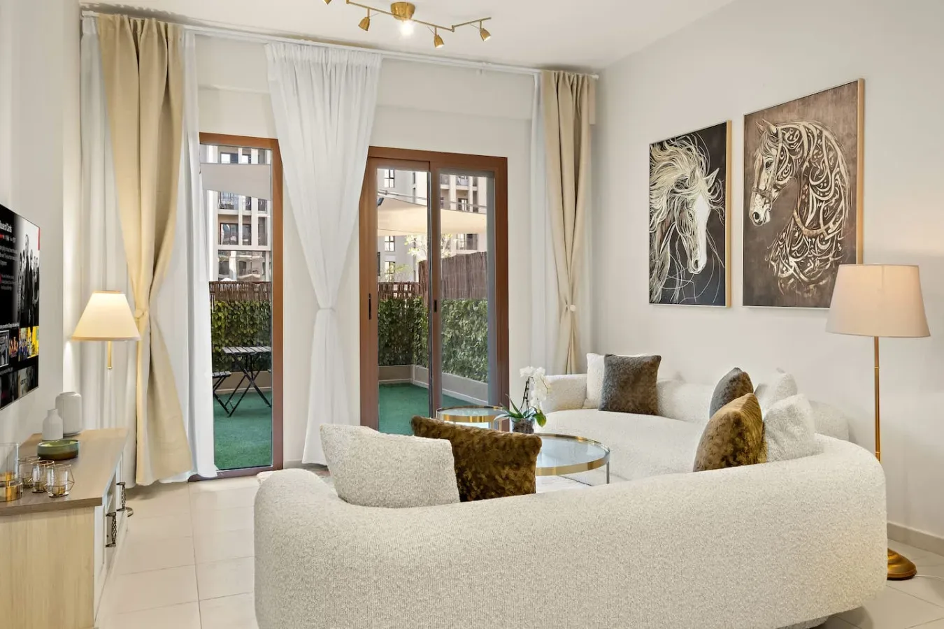 A bright living room with curved seating, glass doors, and artwork on the wall.