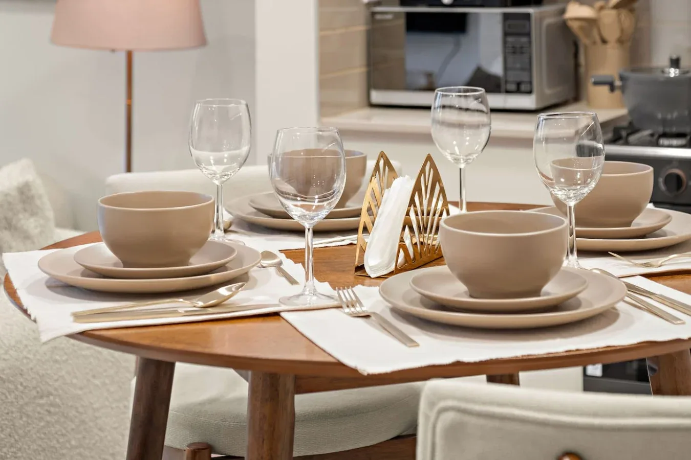A dining table is set with bowls, plates, glasses, and folded napkins.