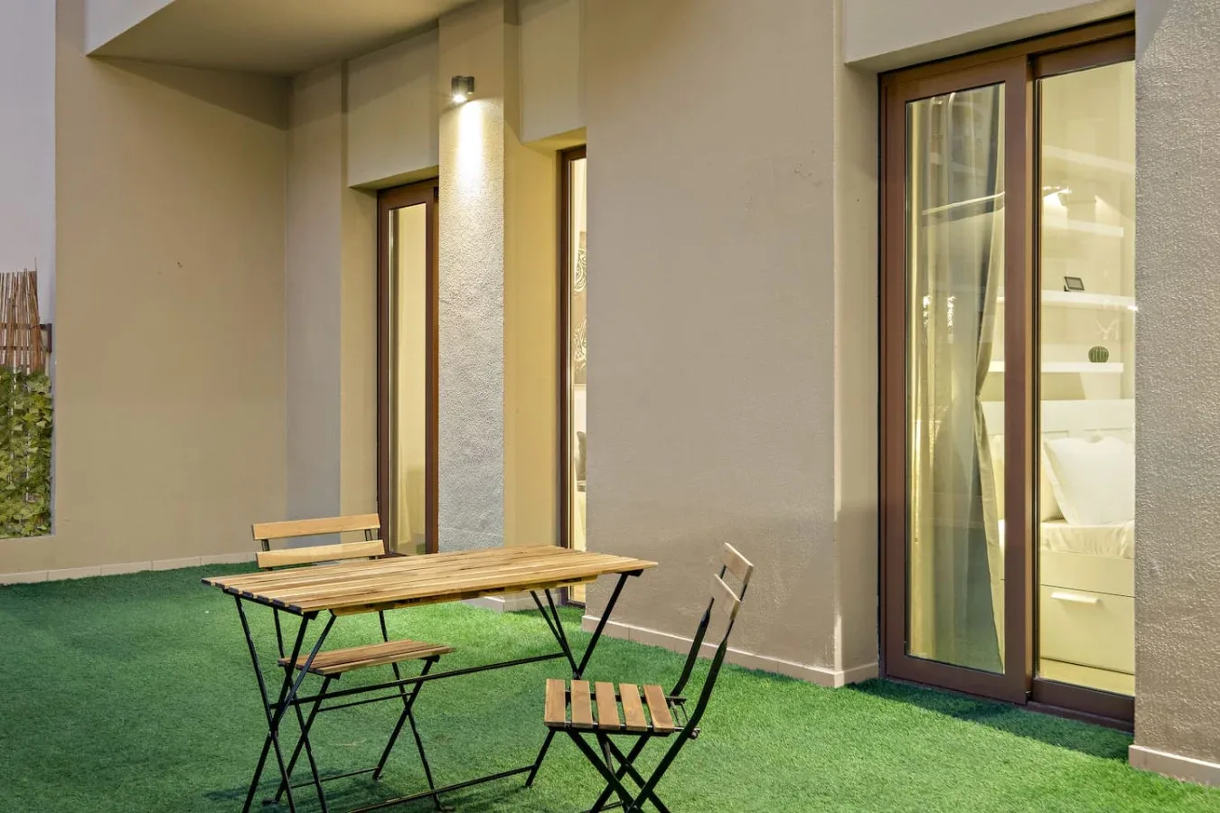 A patio with a folding table and chairs on artificial grass.