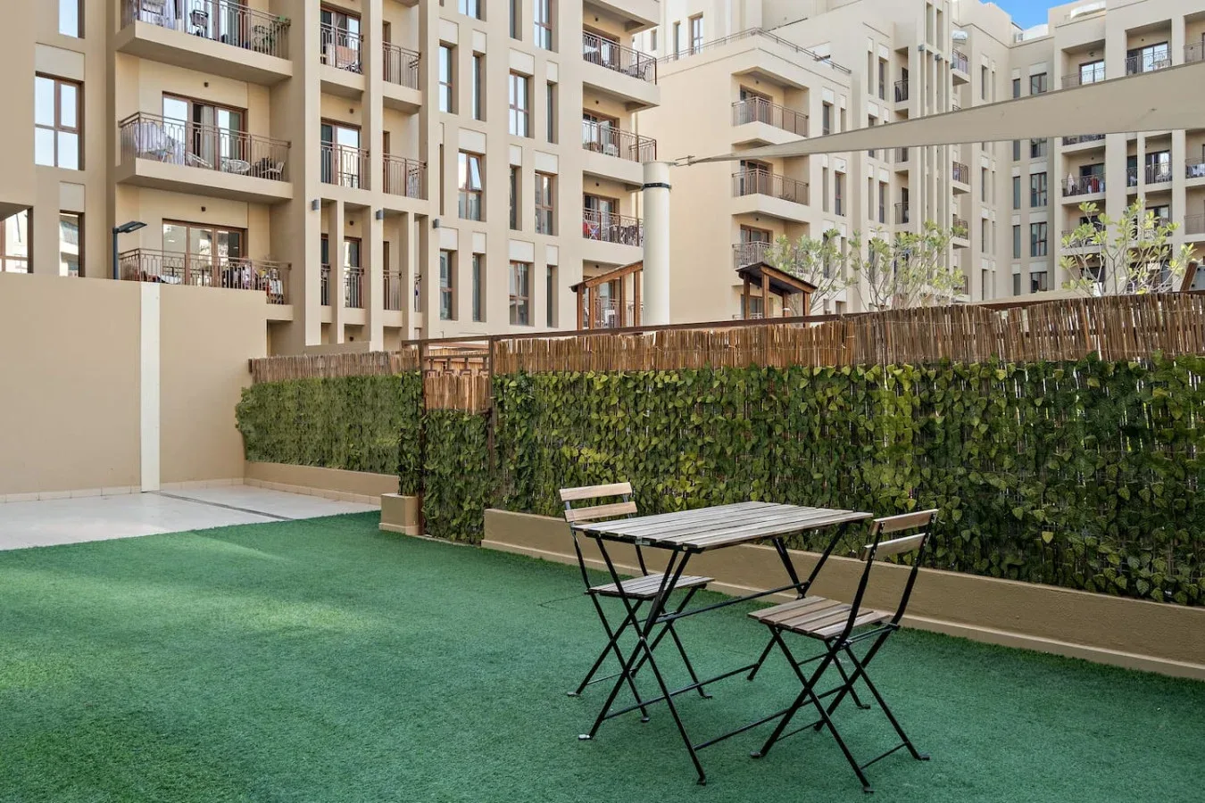 An outdoor courtyard with artificial turf and a small table with chairs.