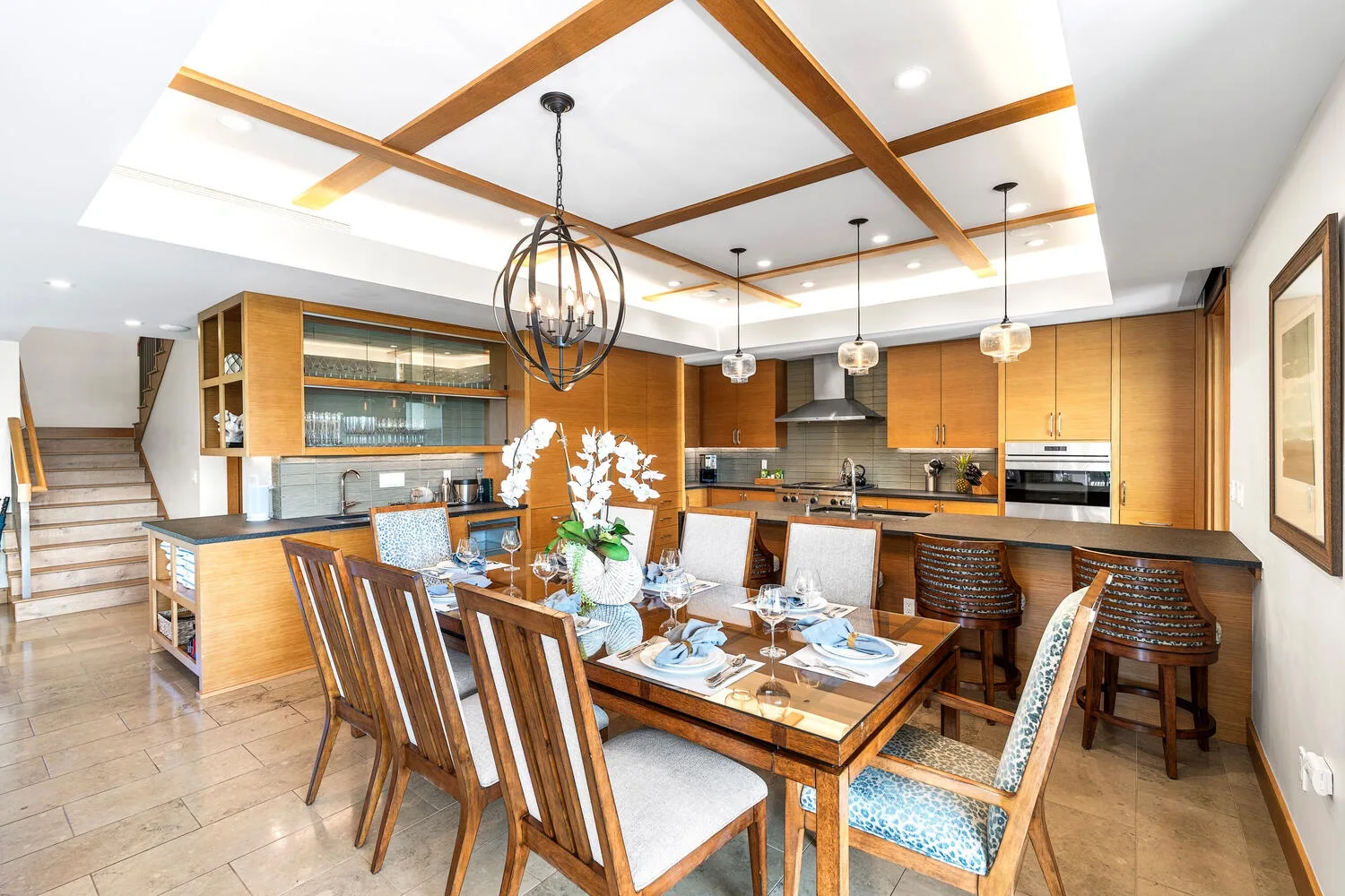 Un comedor se abre a una cocina, con una mesa bajo un techo con vigas.