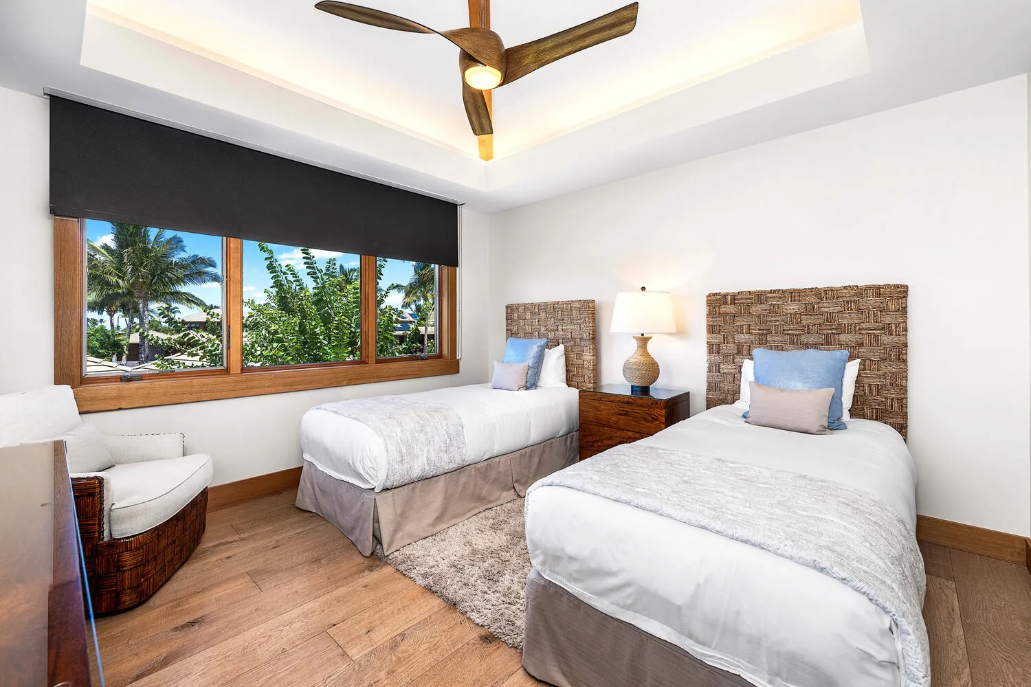 Un dormitorio luminoso con dos camas y una amplia ventana con vistas a la vegetación.