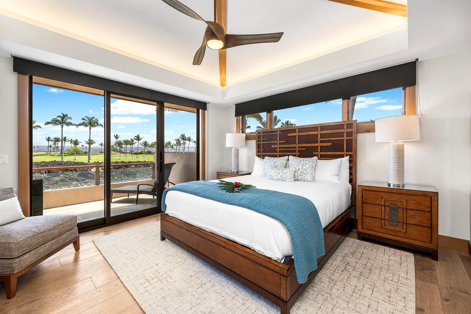 Un dormitorio luminoso con una cama, grandes ventanas y un ventilador de techo.