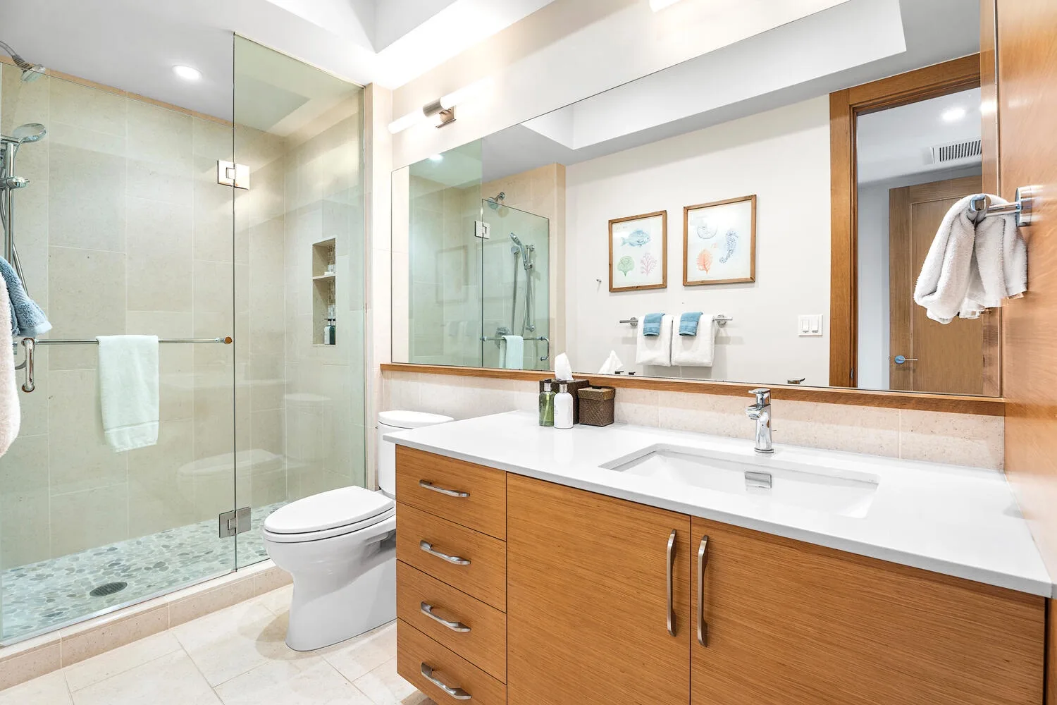 Un baño luminoso con ducha de vidrio, inodoro y tocador de madera.