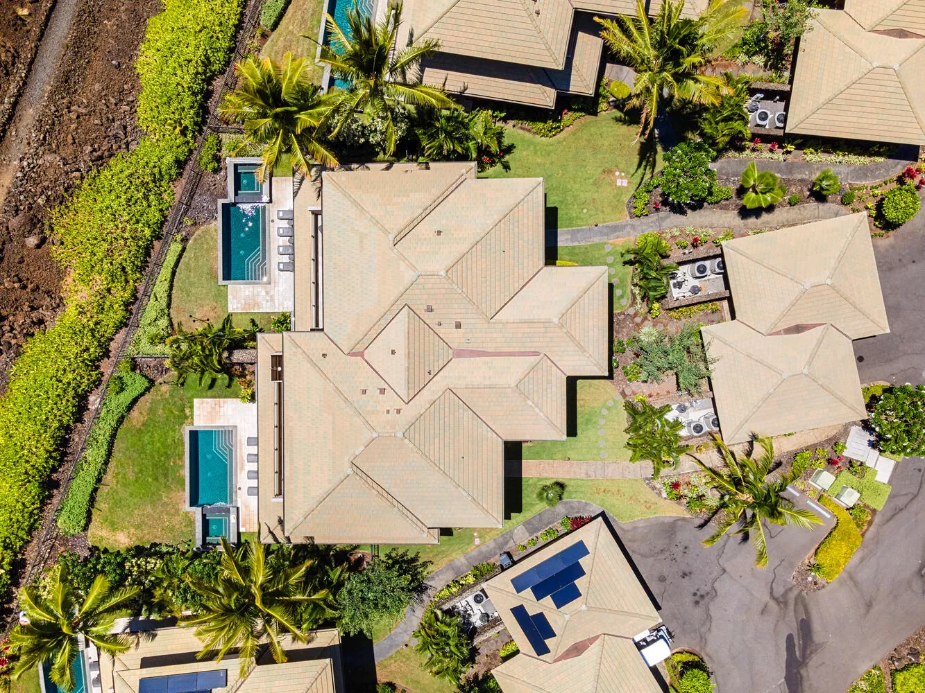 Vista aérea de varios edificios rodeados de jardines y palmeras.