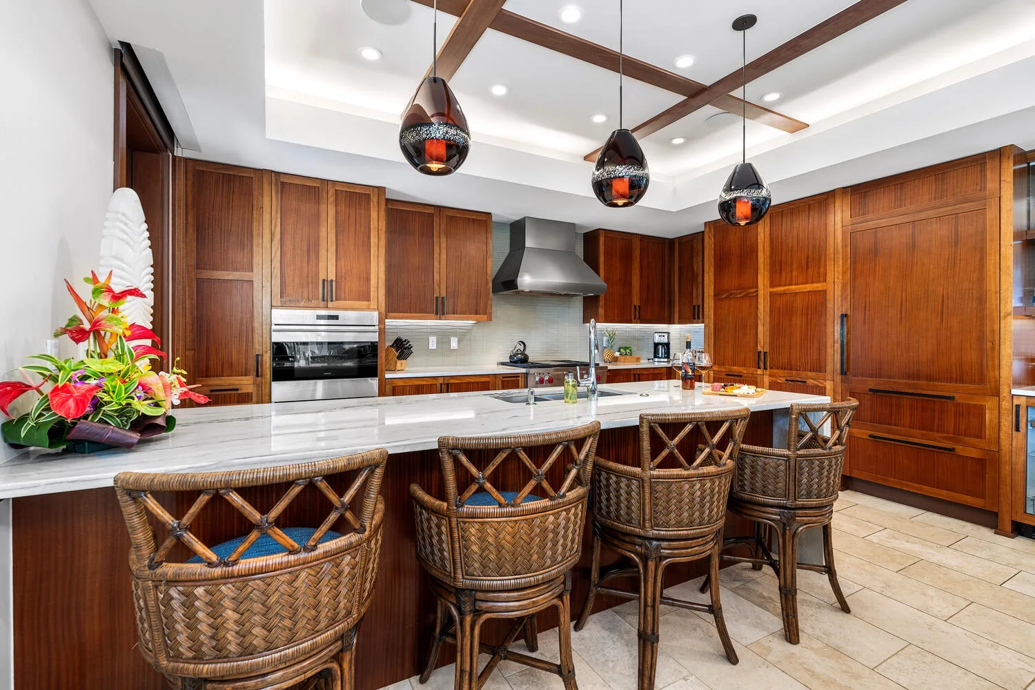 Una cocina amplia con gabinetes de madera oscura y una larga isla con asientos tejidos.