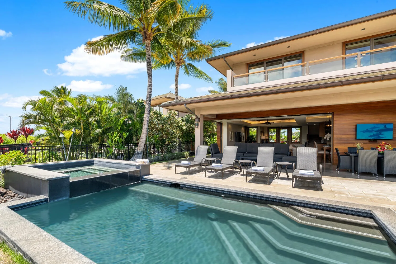Una piscina exterior está junto a una casa moderna y una zona de asientos.