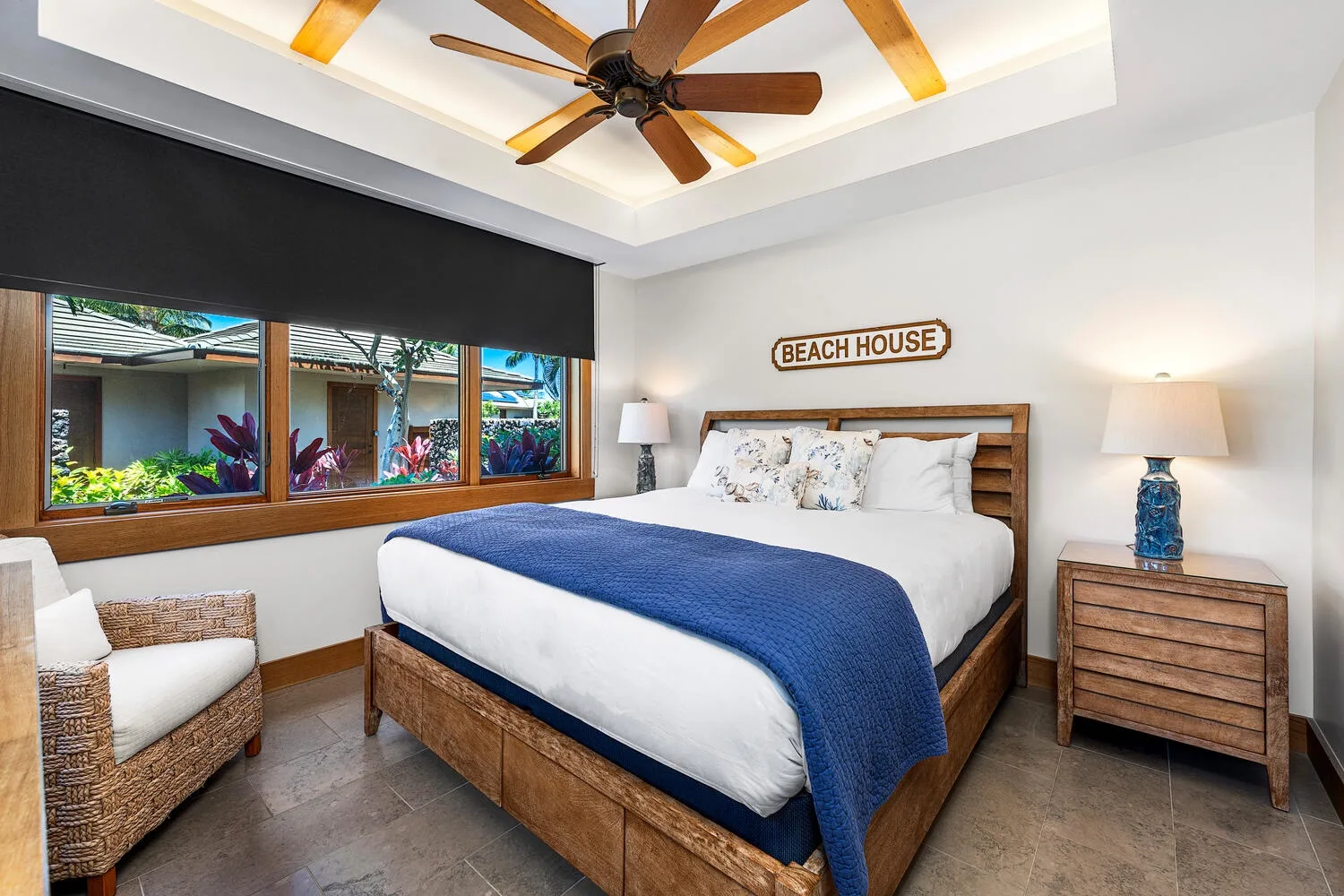 Un dormitorio con una cama de madera, ropa de cama blanca y una manta azul.