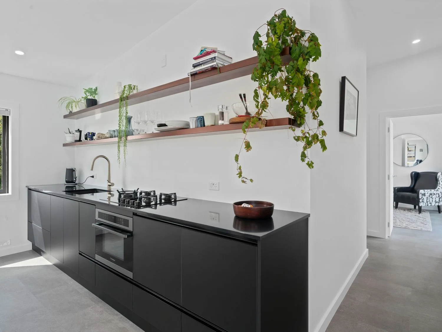 A kitchen with dark cabinets and a countertop, with open shelves above.