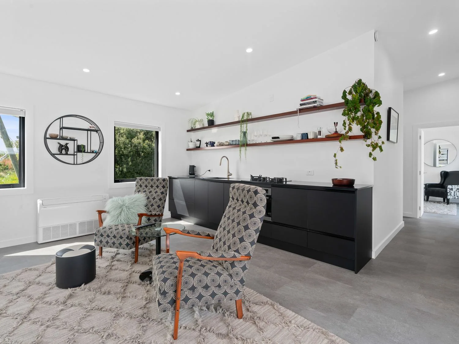 Una zona de cocina con armarios negros y estantes abiertos junto a dos sillones estampados y una mesa de cristal en Caledonia - Earnscleugh Holiday Home, en Earnscleugh