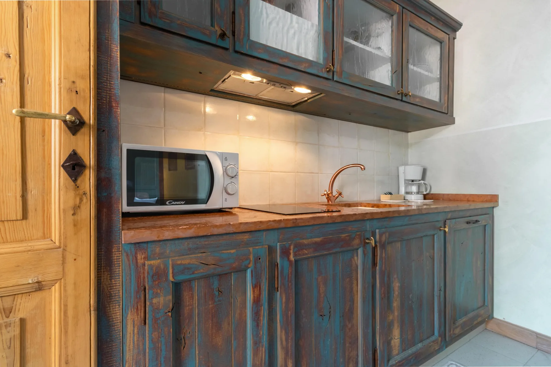 A compact kitchen area with a microwave, countertop, and blue cabinets.