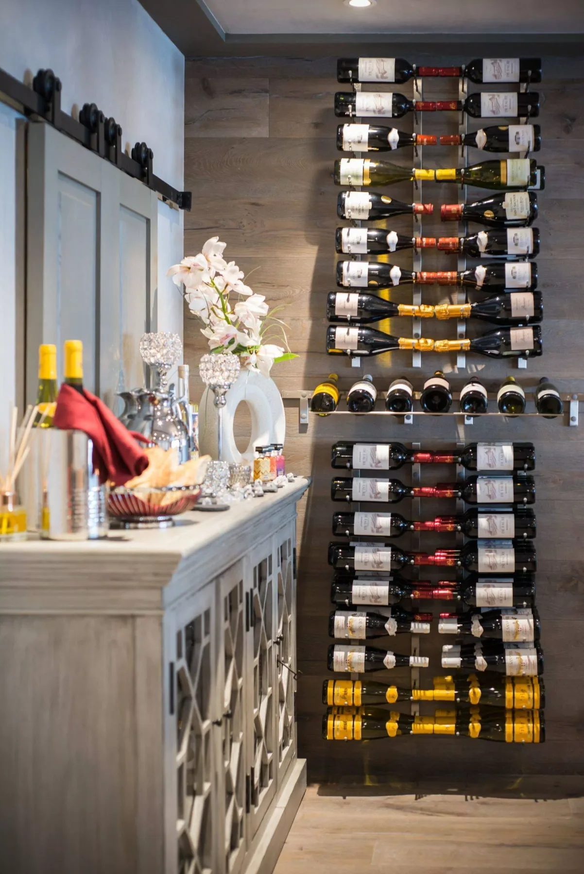 A wine display room features wall-mounted bottle racks and a counter with flowers.