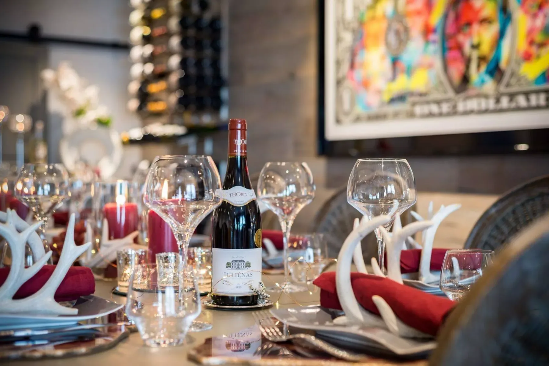 Una mesa de restaurante está puesta con copas de vino, servilletas y una botella de vino.