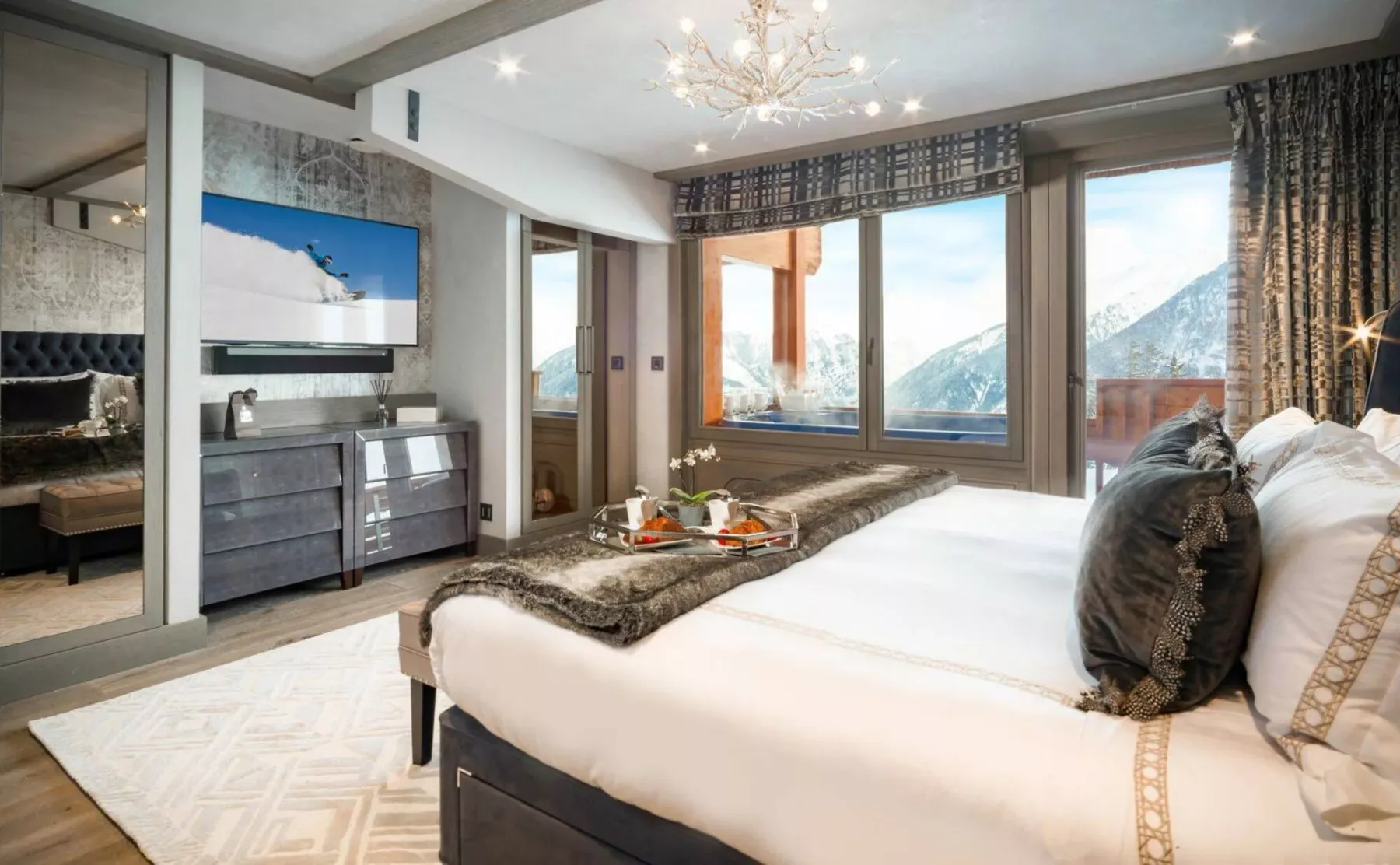 Un dormitorio con una cama grande frente a ventanas con vistas a las montañas.