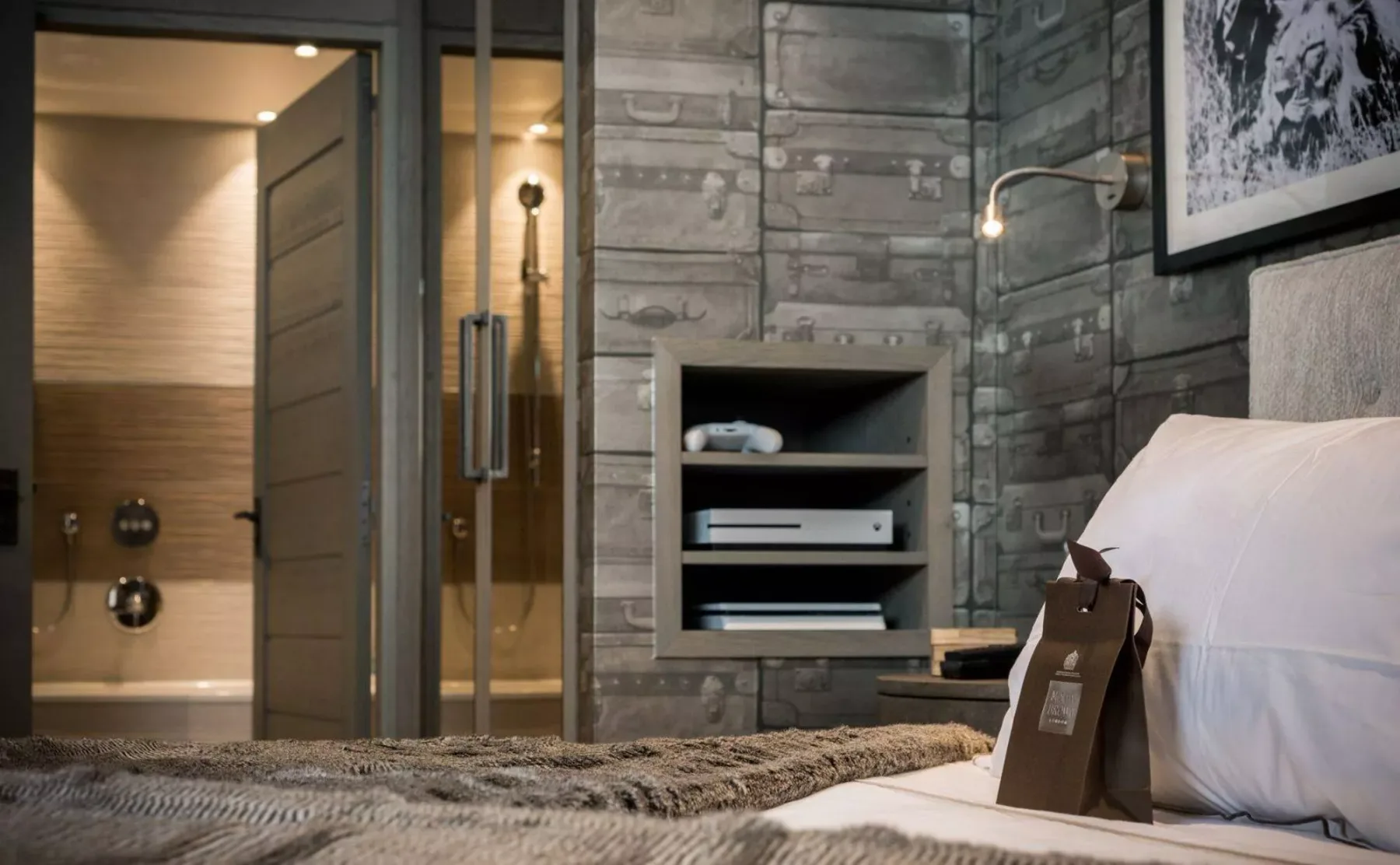 Un dormitorio con una cama junto a una estantería empotrada y una puerta de vidrio al baño.