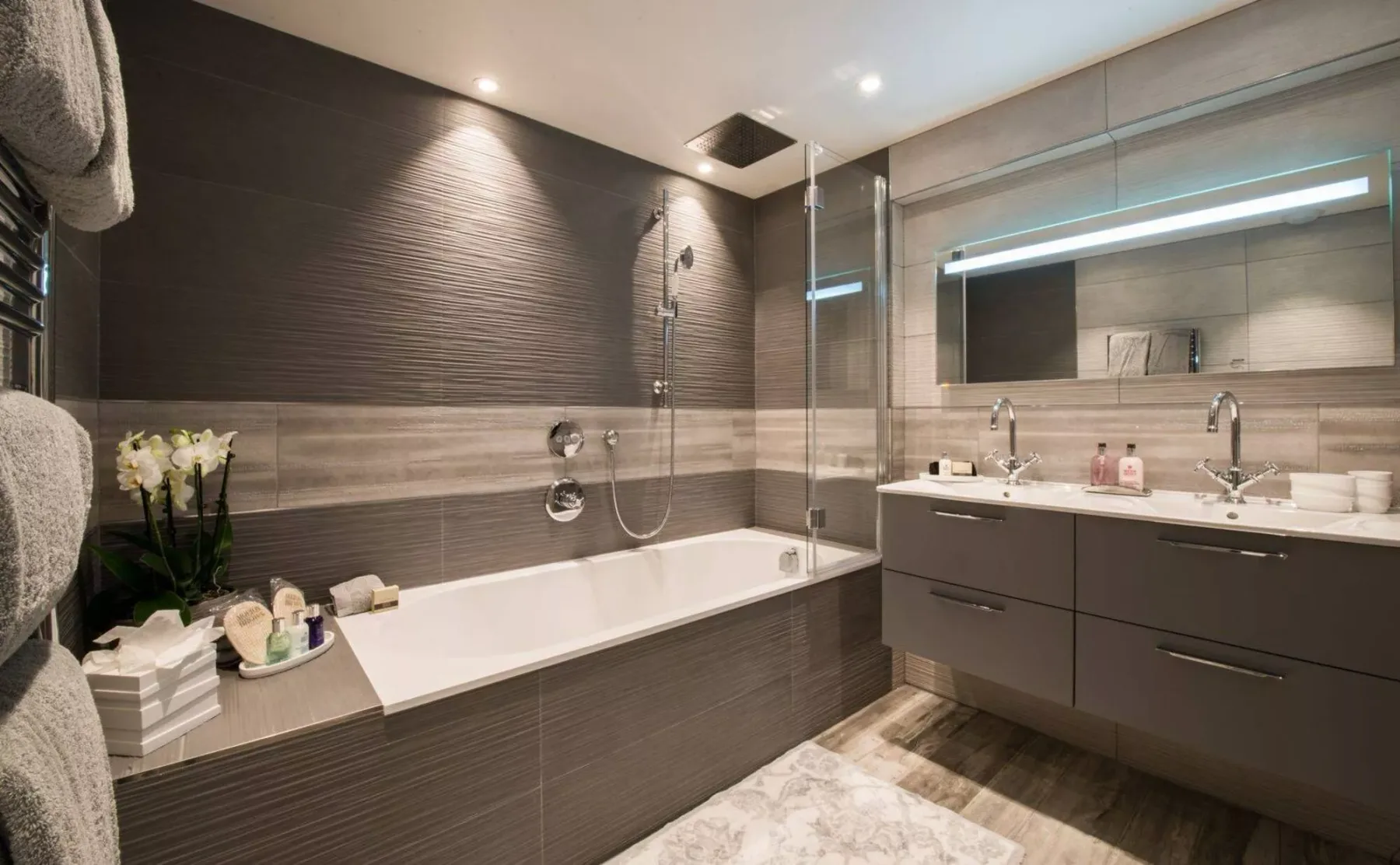Un baño moderno con bañera, mampara de vidrio y lavabo.