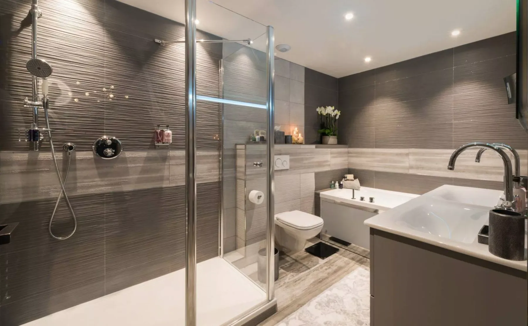 Un baño moderno con una ducha de vidrio y un lavabo blanco.