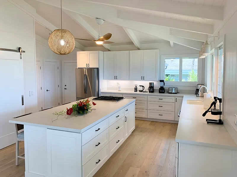 Una cocina luminosa con gabinetes blancos, una isla y una ventana sobre la encimera.