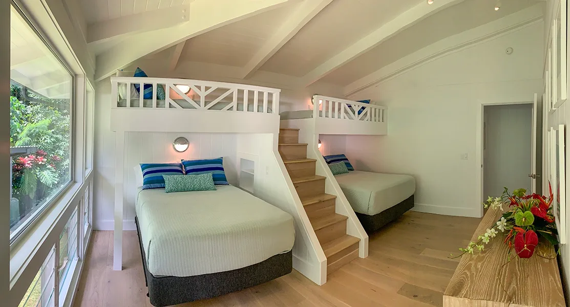 Un dormitorio luminoso con dos zonas elevadas para dormir y una escalera de madera.