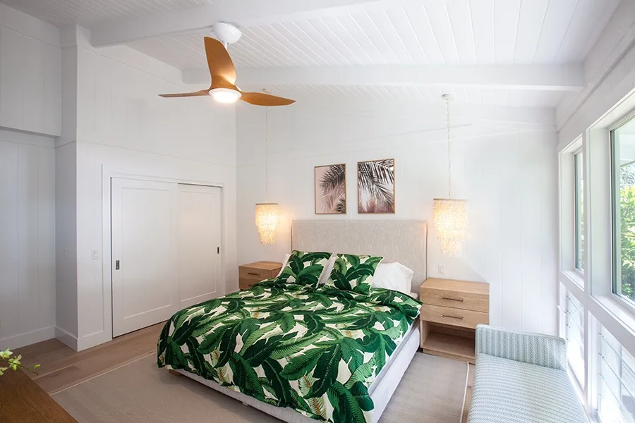 Un dormitorio luminoso con una cama cubierta con ropa de cama de hojas verdes.