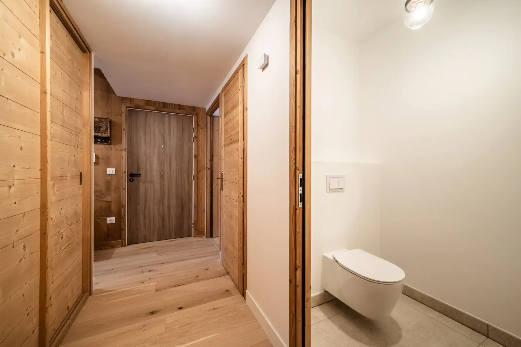 A bathroom with wooden walls and a toilet.