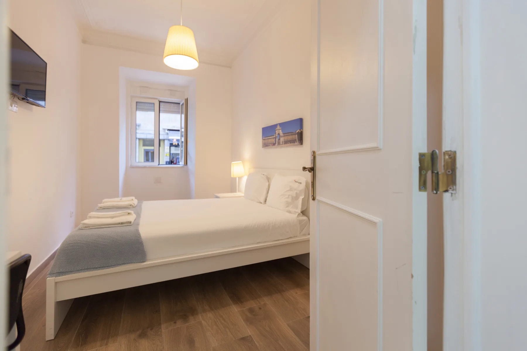 A bedroom with a bed, bedside lamp, and window.