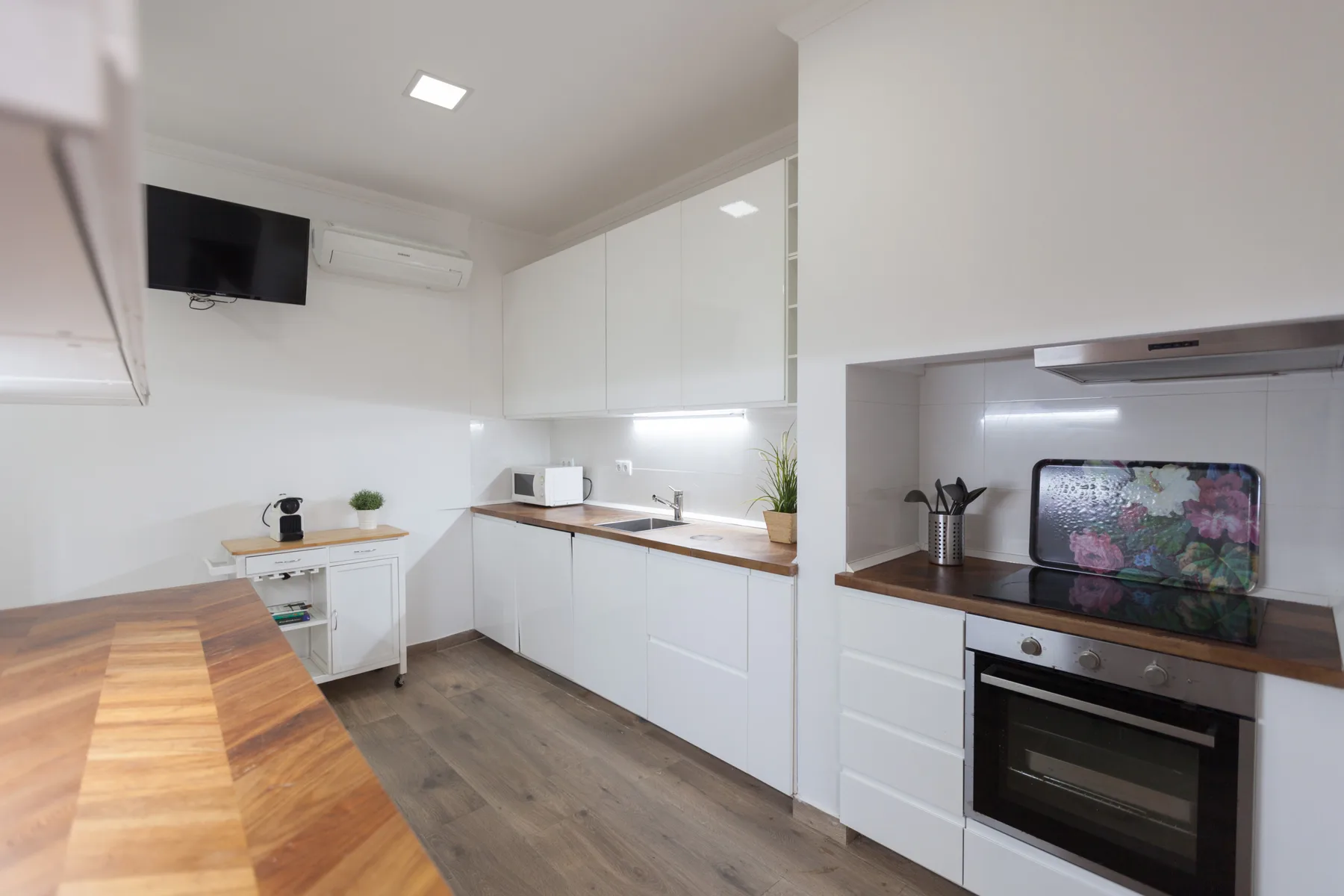 A modern kitchen with white cabinets, countertops, and built-in appliances.
