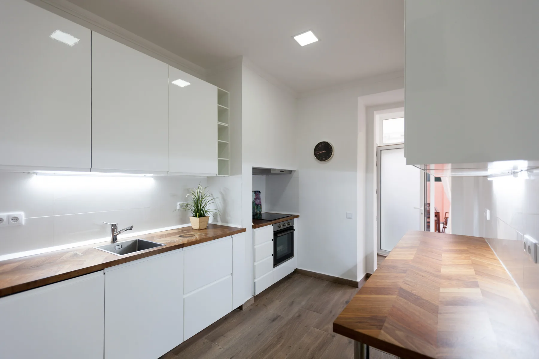 A bright kitchen with white cabinets, a wood countertop, and a dining table.