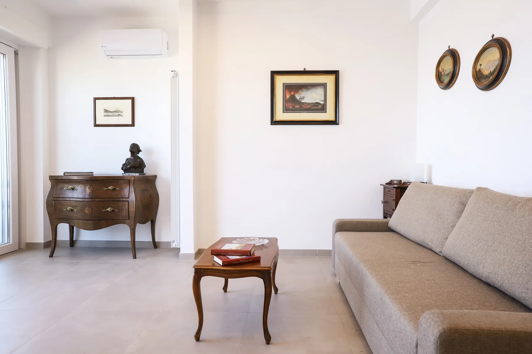 A bright living room with seating, a coffee table, and framed artwork.