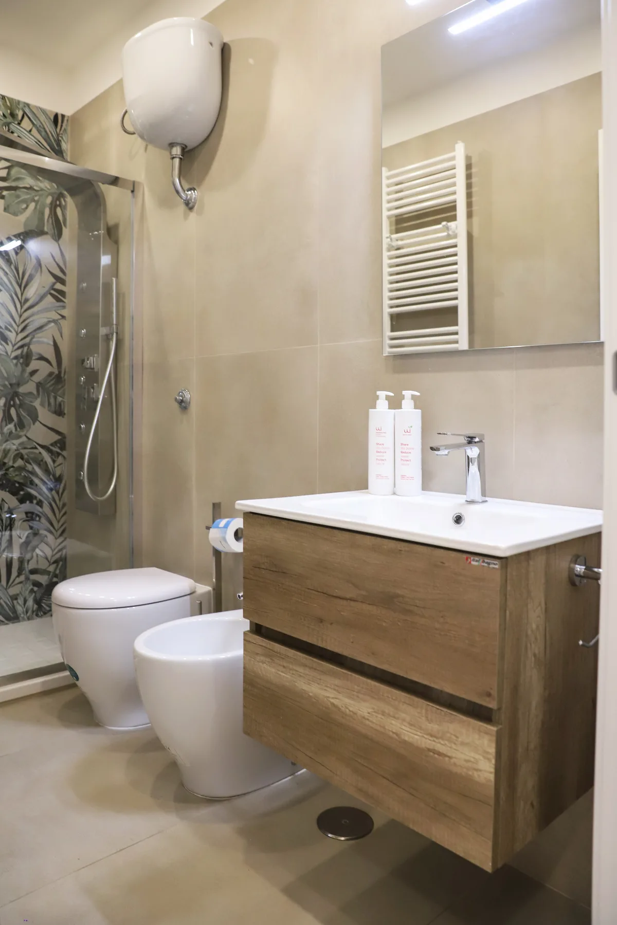 A tiled bathroom with a sink vanity, toilet, and patterned shower screen.