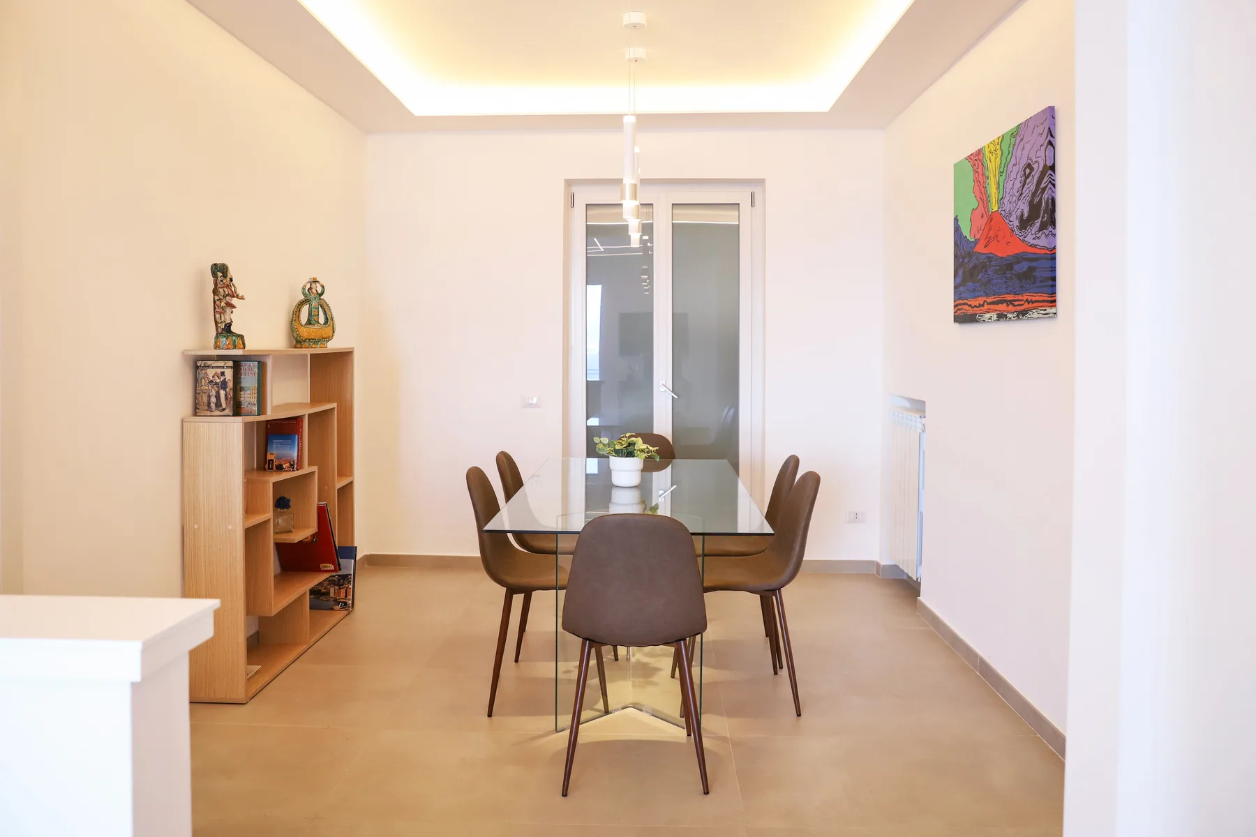 A bright dining area with a table, seating, and a bookcase.