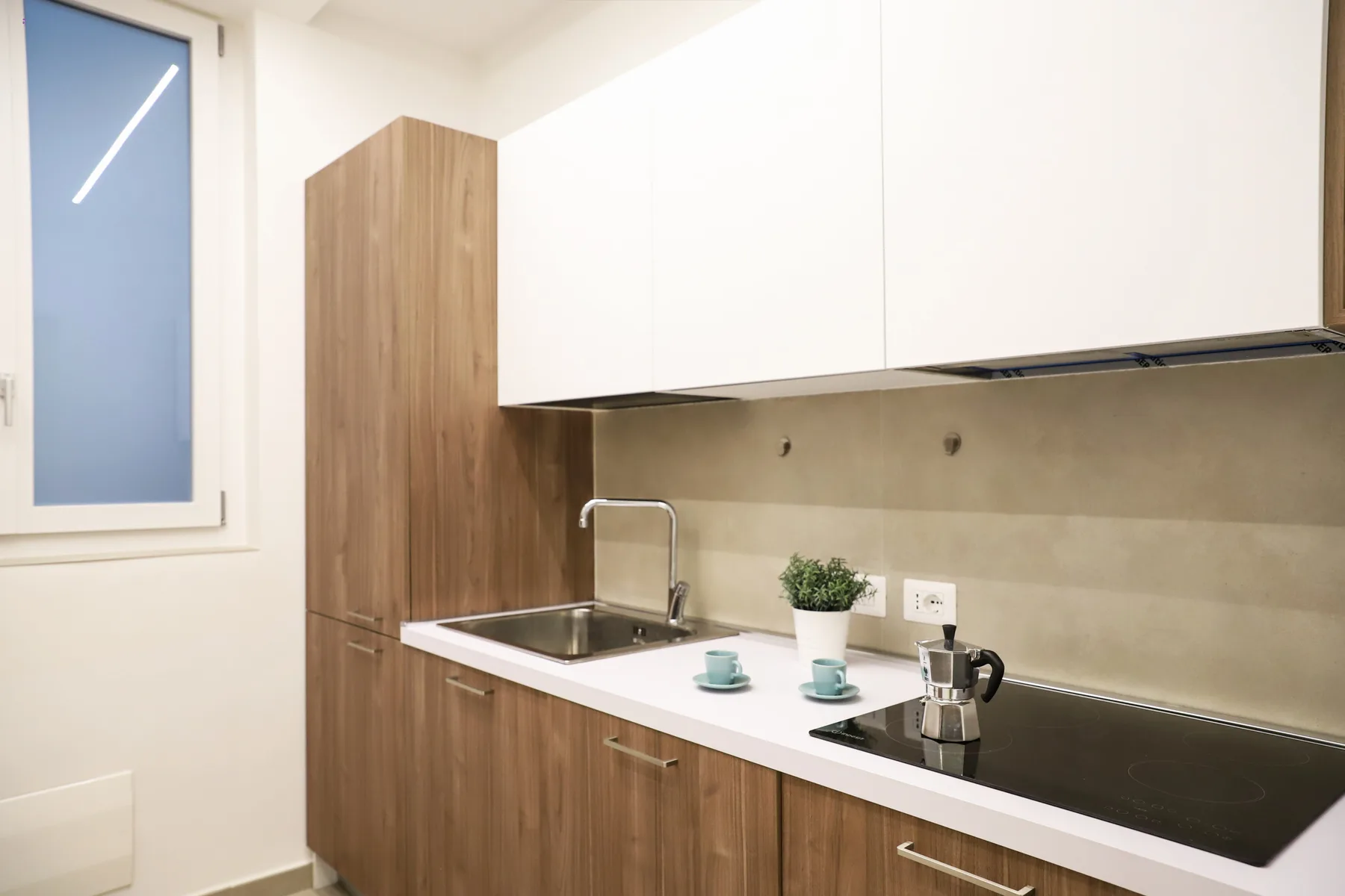 A compact kitchen with wood cabinetry, a countertop, and a cooktop.