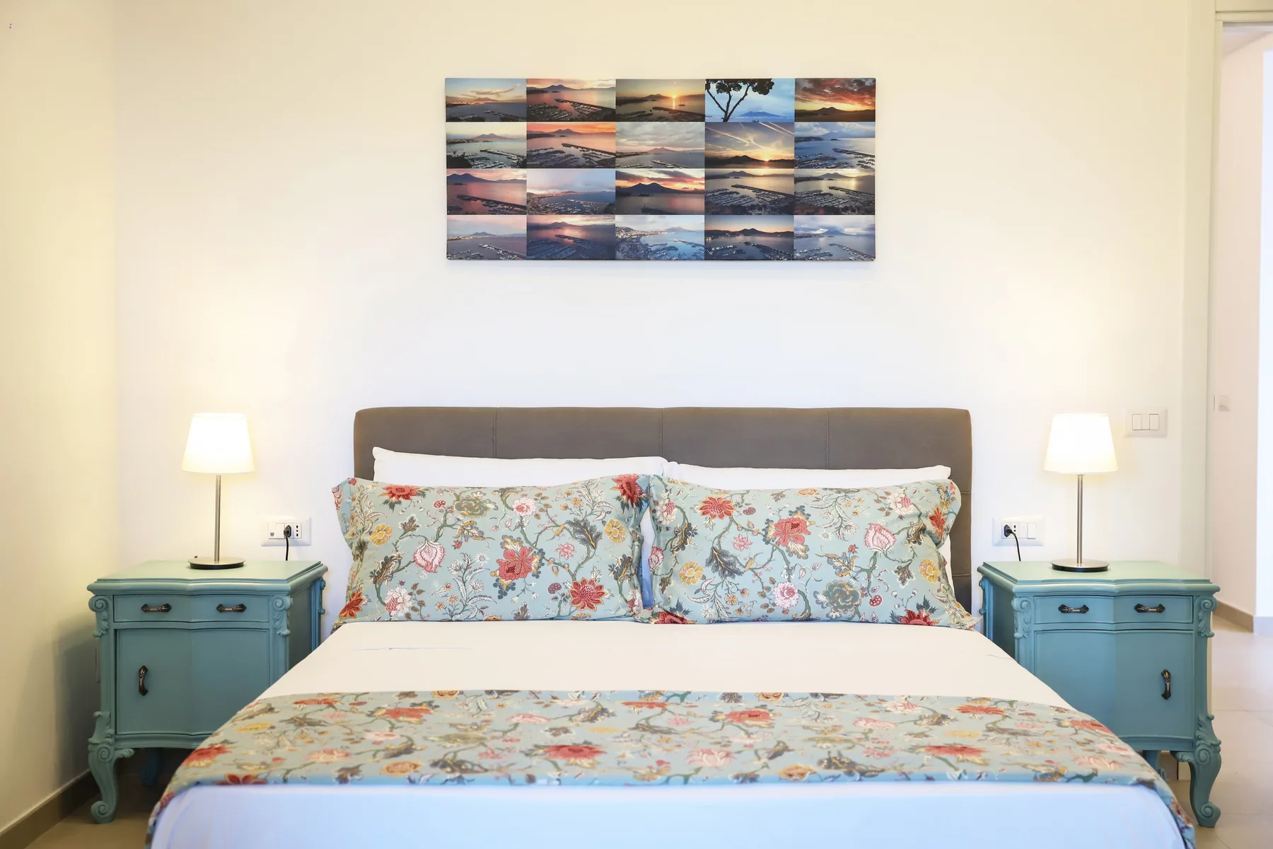A bedroom with a bed, floral bedding, and matching bedside tables.