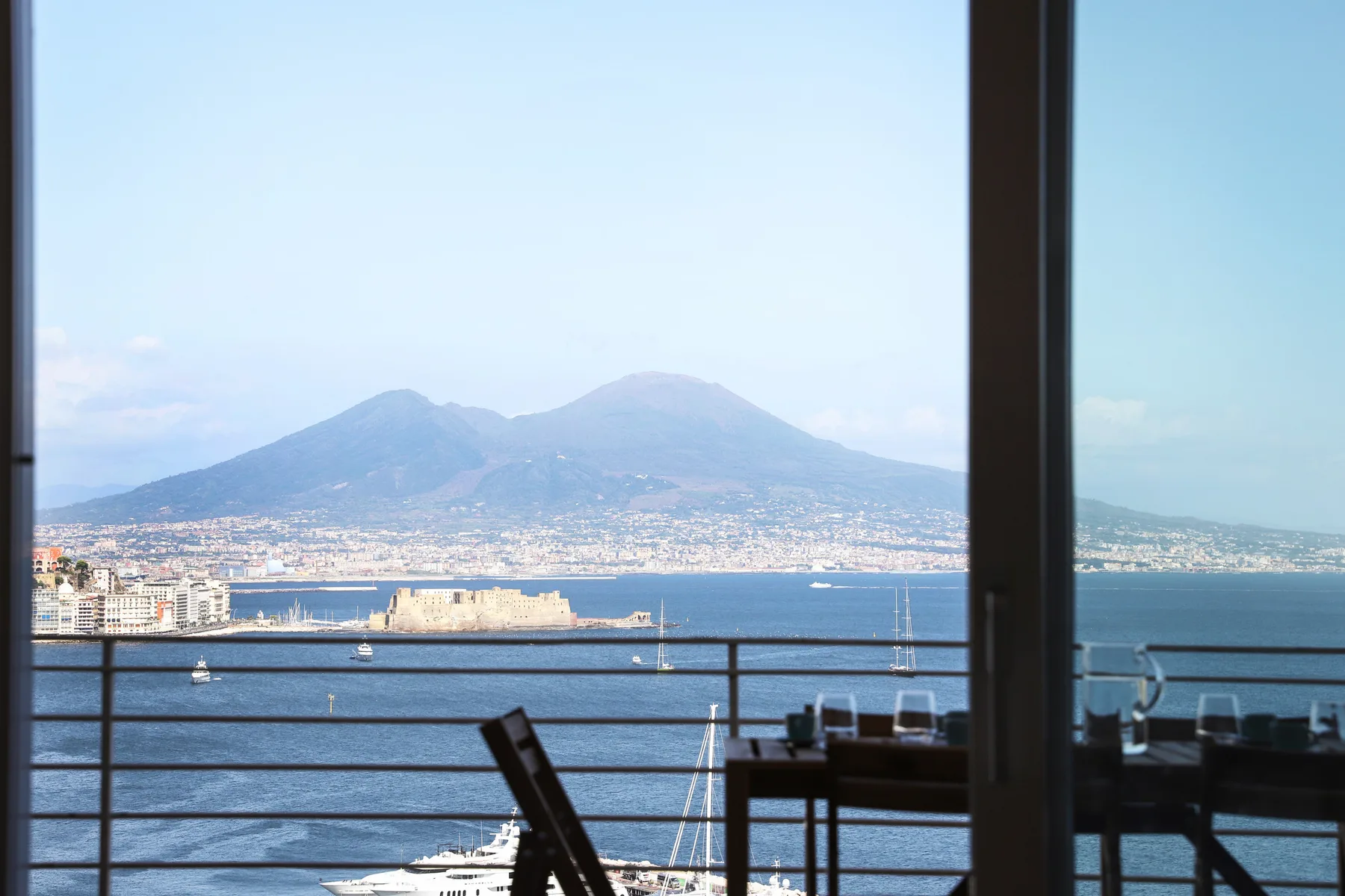 A waterfront view of a bay and distant mountains seen through a window.