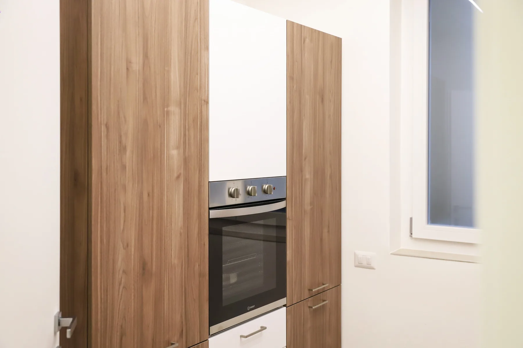 A modern kitchen with a built-in oven and wood-finish cabinets.