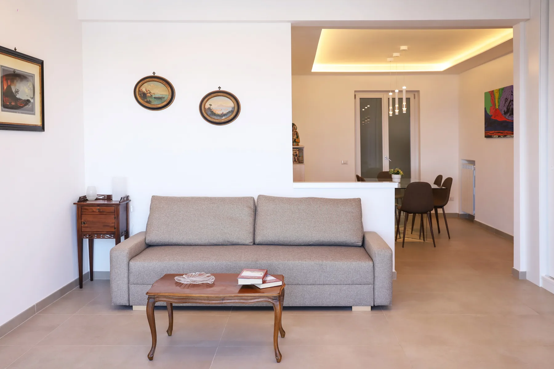 A living room with a sofa and coffee table opens onto a dining area.