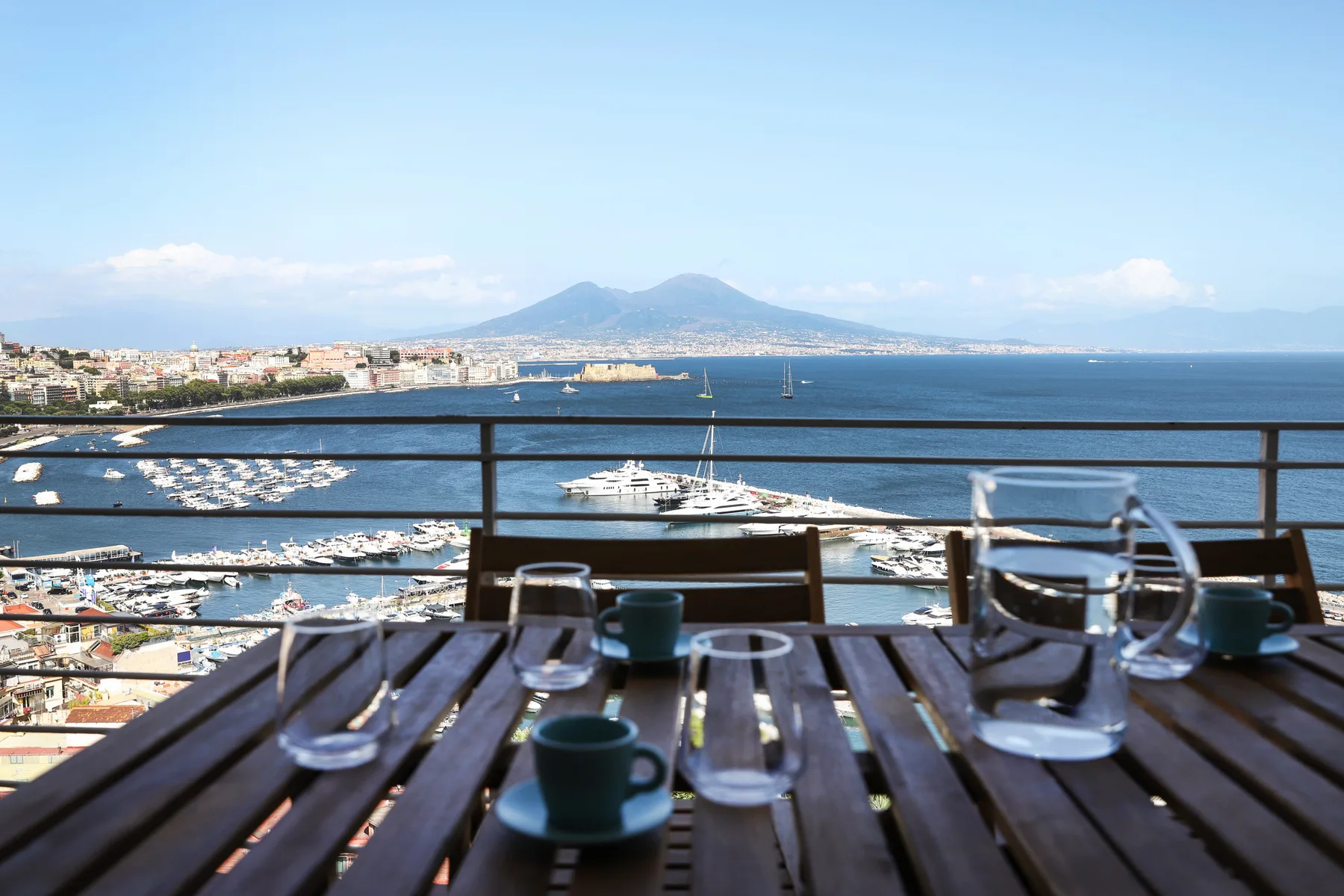 A waterside dining table overlooks a marina and a distant mountain.