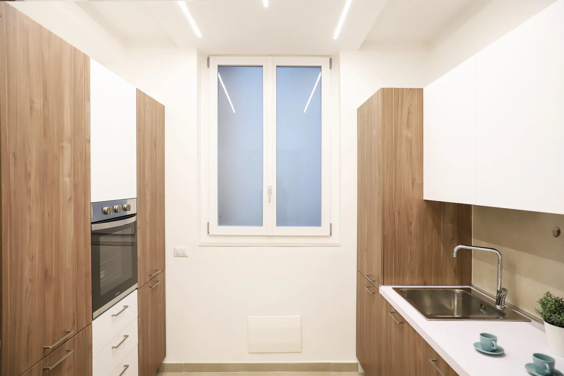 A bright kitchen with wood cabinetry, an oven, and a sink.