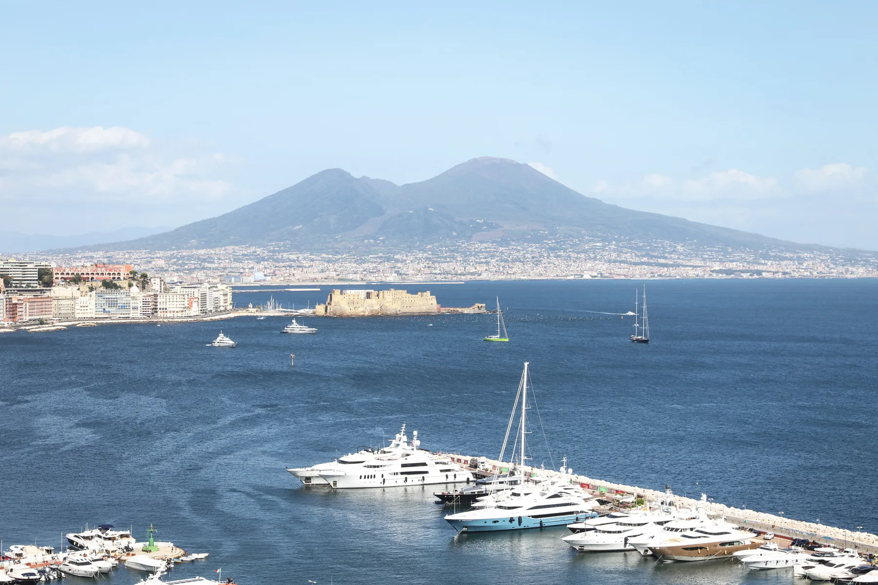 A coastal harbor with moored yachts and a mountain across the water.