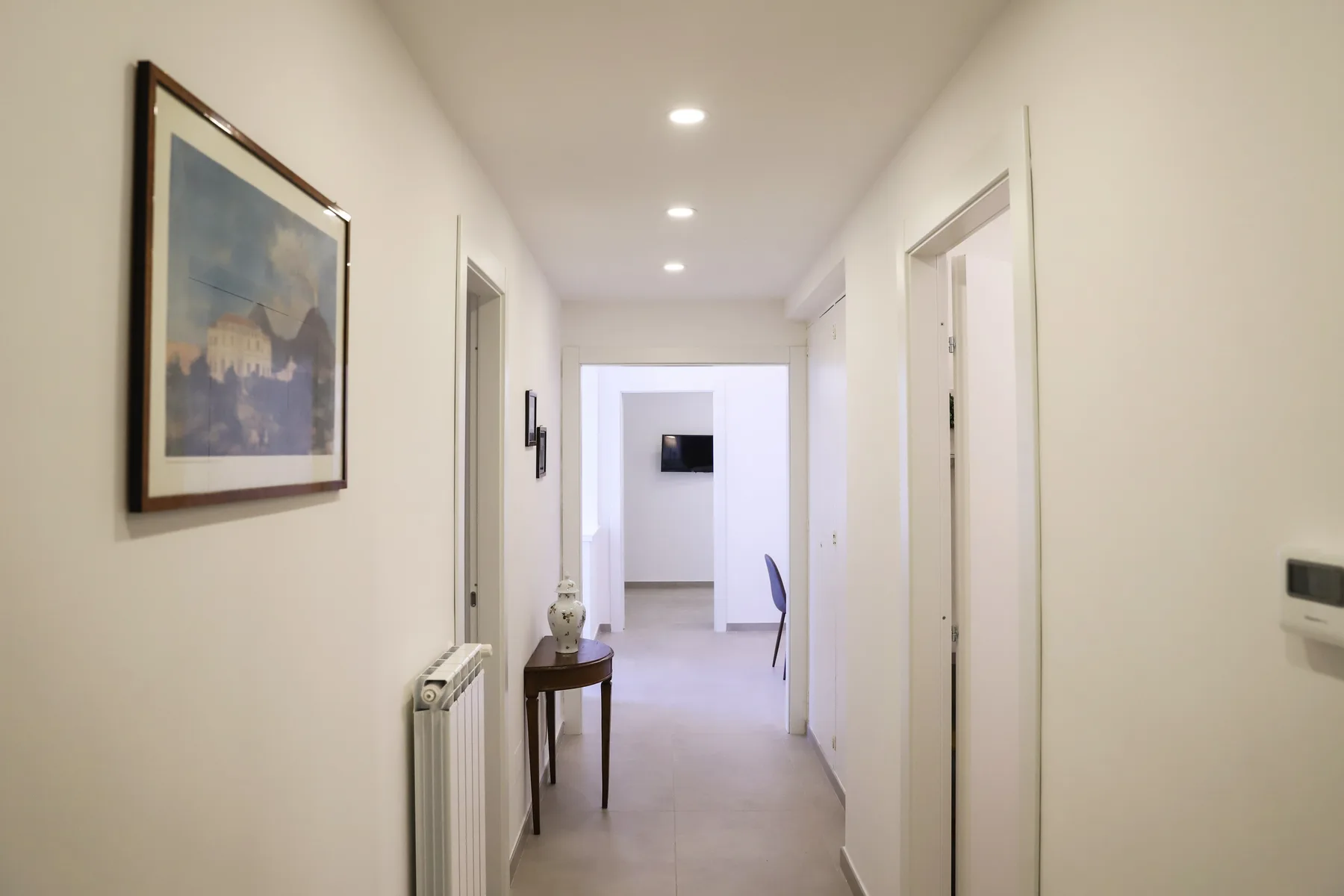 A bright hallway with several doorways and a framed picture on the wall.