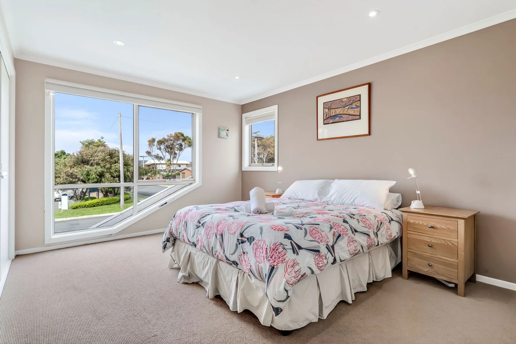 Un dormitorio con una cama cubierta con ropa de cama floral junto a una ventana grande.