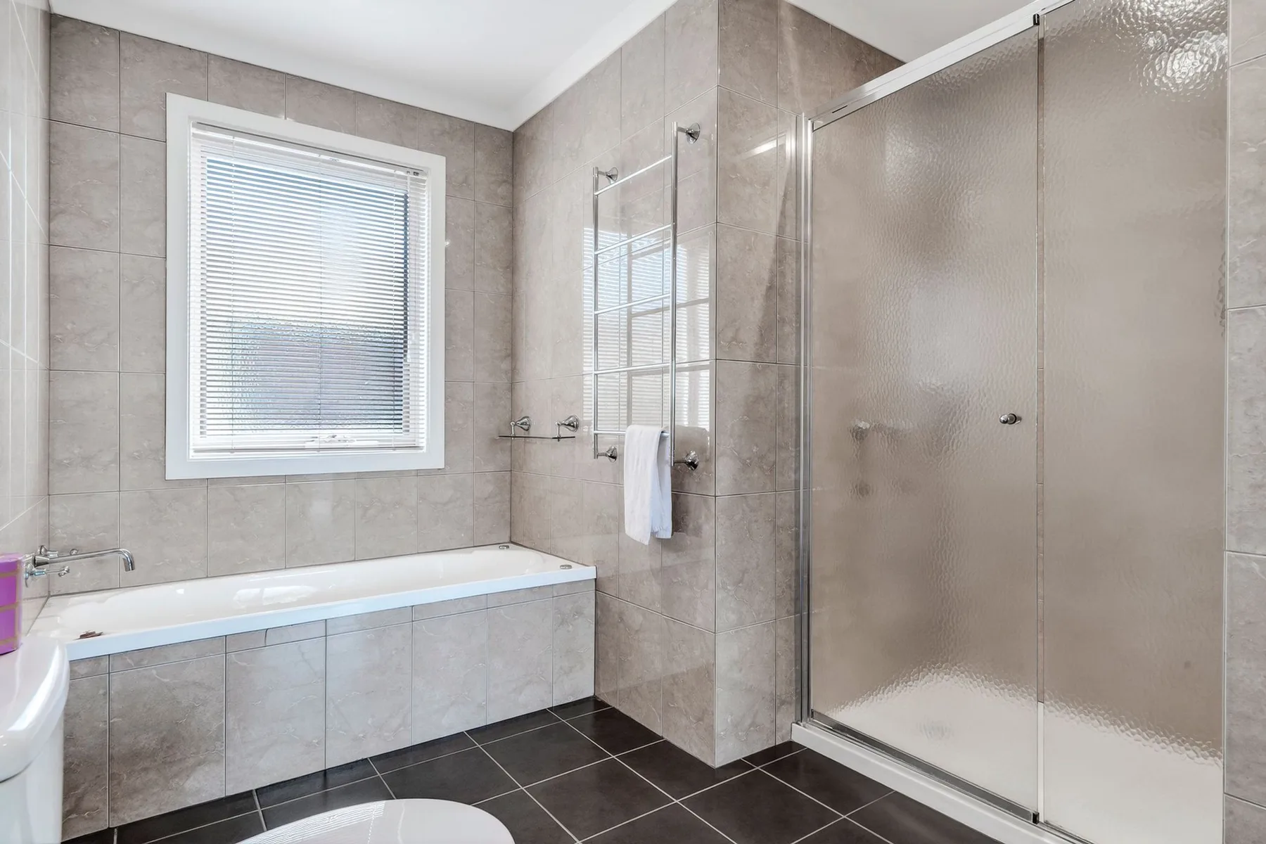 Baño con azulejos, bañera, ducha y ventana.