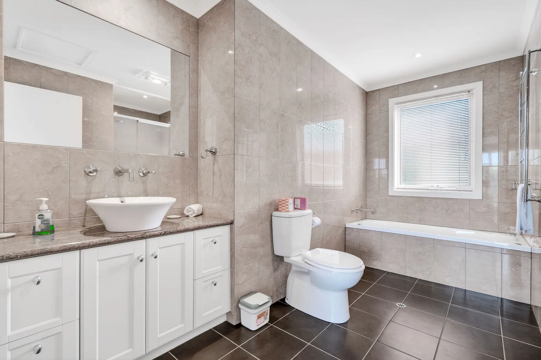 Un baño revestido de azulejos con bañera, inodoro y lavabo.