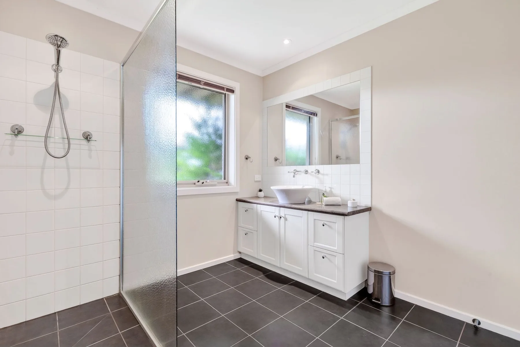 Un baño luminoso con ducha de vidrio y tocador blanco.
