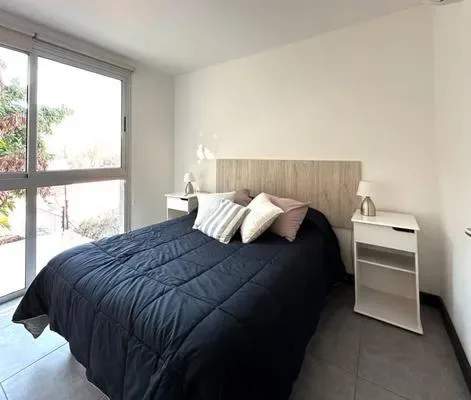 Un dormitorio luminoso con una cama junto a una ventana grande.