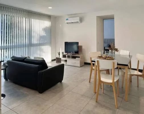 Una luminosa sala de estar y comedor con asientos, un televisor y una mesa de comedor.