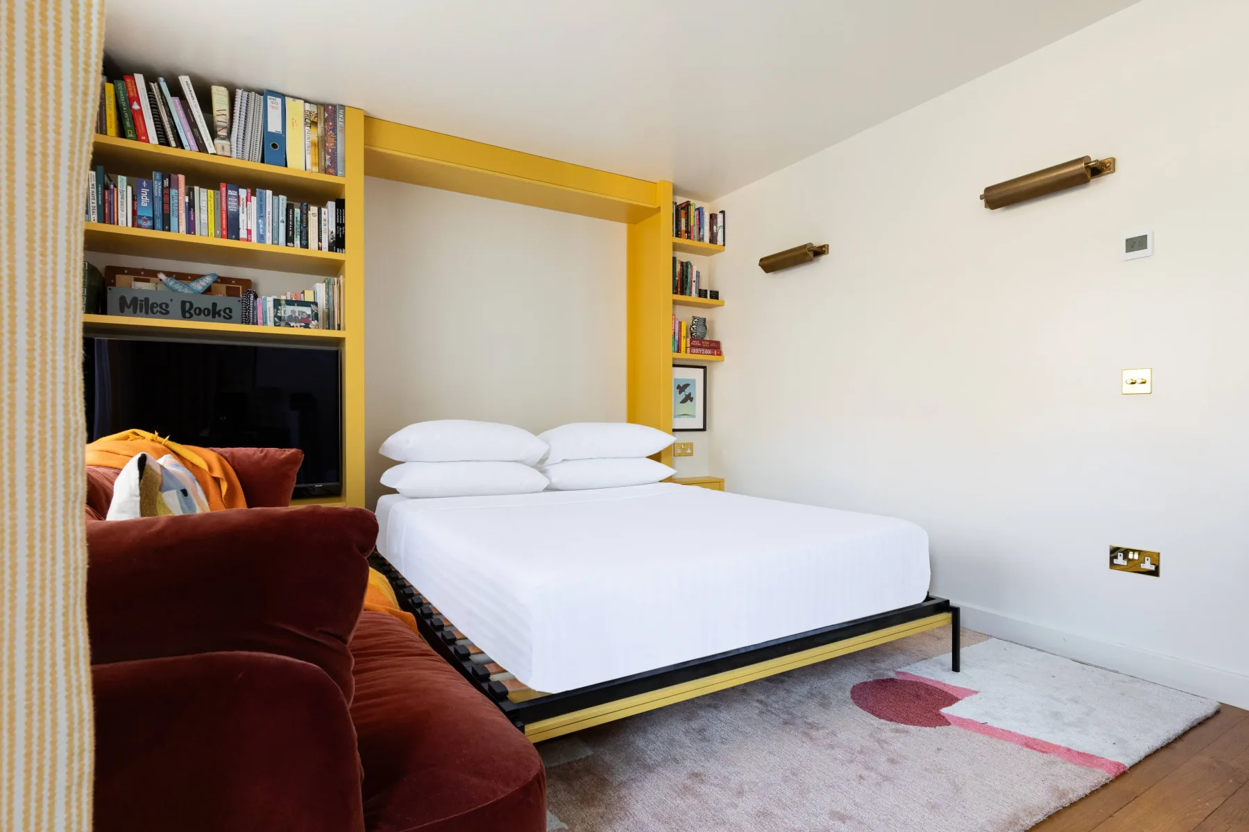 A bedroom with a bed, built-in bookshelves, and a red armchair.
